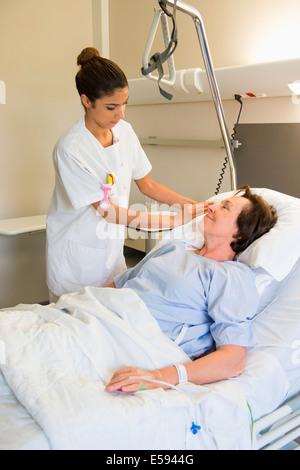 Female nurse attending patient on hospital bed Stock Photo - Alamy