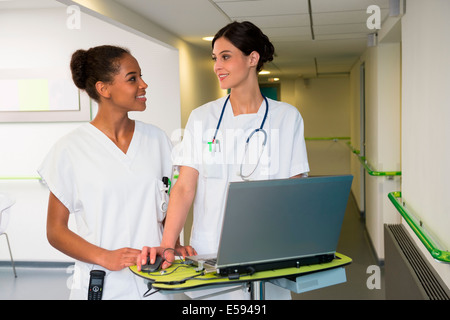 Female doctor and nurse using laptop in hospital corridor