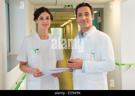 Doctor and nurse smiling in hospital corridor Stock Photo