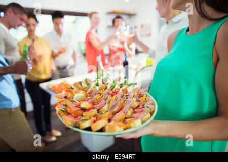 Woman serving tray of food at party Stock Photo