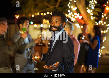 Man gesturing with wine at party Stock Photo