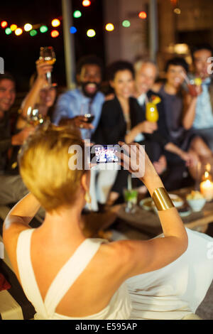 Woman taking picture of friends at party Stock Photo