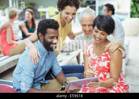 Friends using digital tablet at party Stock Photo