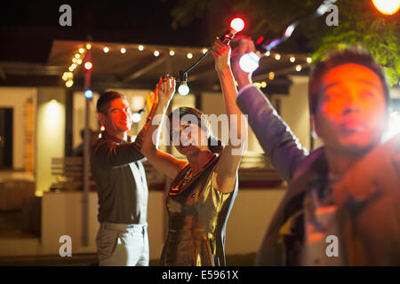 Friends stringing lights at outdoor party Stock Photo