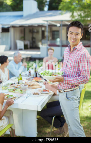 Man serving friends at table outdoors Stock Photo