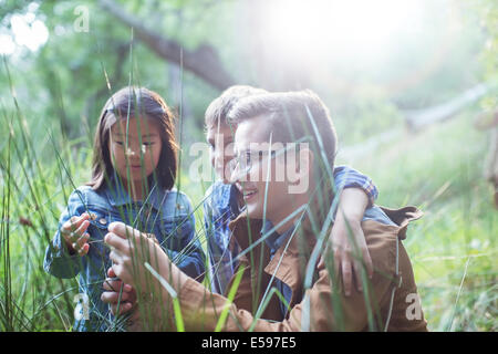 Students and teacher examining grass in forest