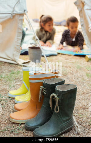 Rainboots lined up outside tent at campsite Stock Photo