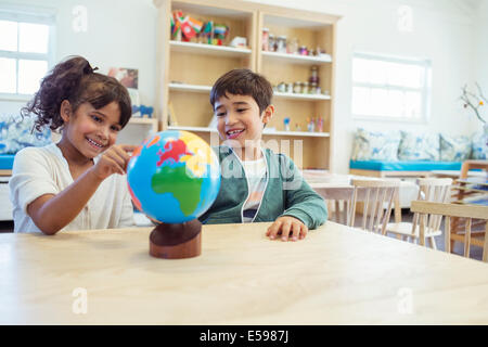 Students examining globe in classroom Stock Photo