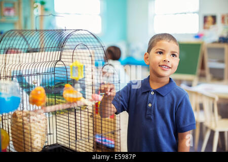 Student examining birdcage in classroom Stock Photo