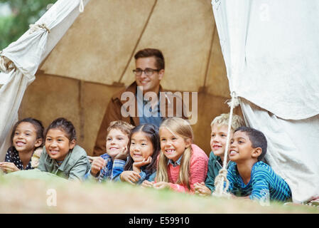 Students and teacher smiling in tent at campsite Stock Photo