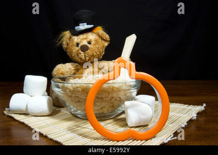 Cute thanksgiving pilgrim bear making pumpkin shaped puffed rice cereal cookie treats Stock Photo