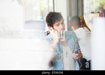 Man listening to mp3 player in cafe Stock Photo