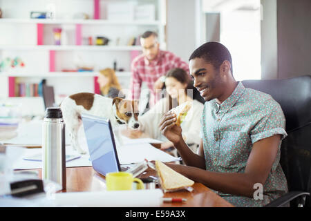 Man eating at conference table in office Stock Photo