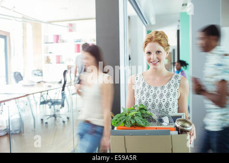 Woman carrying cardboard box in office Stock Photo