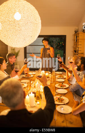 Woman giving toast at dinner party Stock Photo