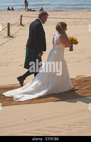 Bride arrives at beach wedding escorted by man wearing kilt at Bournemouth beach in July  Credit:  Carolyn Jenkins/Alamy Live News Stock Photo