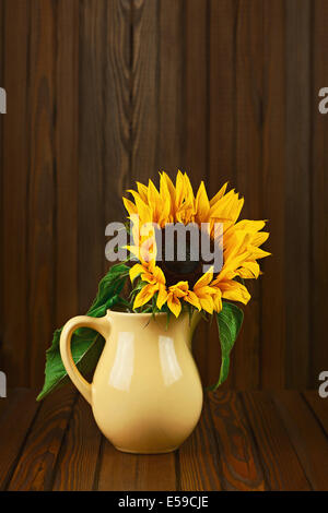 Still life with sunflower in vase on wooden background. Closeup. Stock Photo