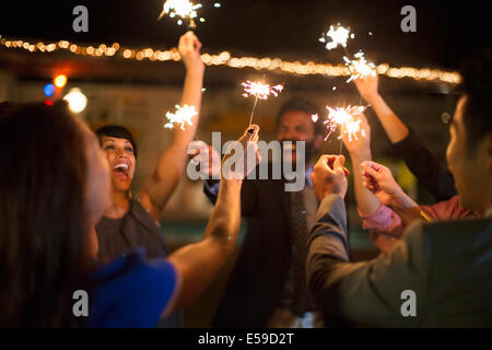 Friends playing with sparklers at party Stock Photo