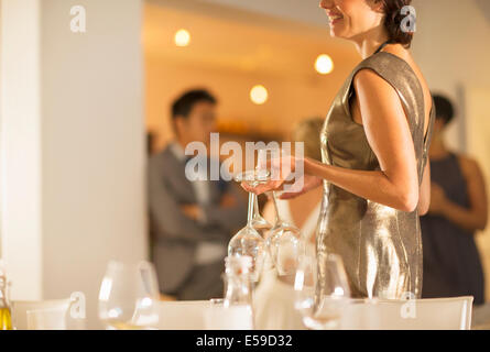 Woman setting table at dinner party Stock Photo