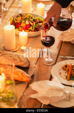 Woman pouring wine at dinner party Stock Photo