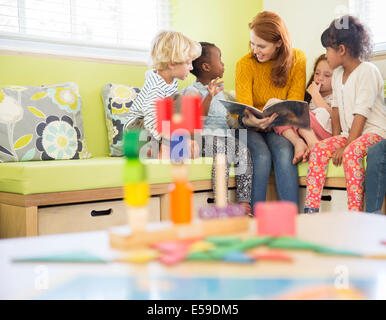 Teacher and students reading in classroom Stock Photo