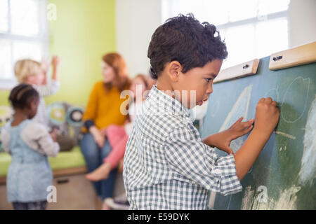 Student drawing on chalkboard in classroom Stock Photo