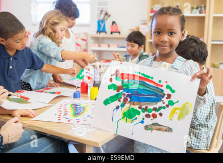 Student showing off finger painting in classroom Stock Photo