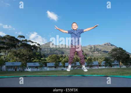 Boy jumping on trampoline outdoors Stock Photo