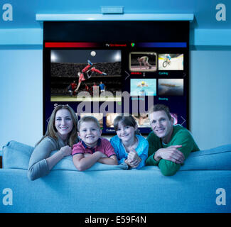 Family watching multi screen television in living room Stock Photo