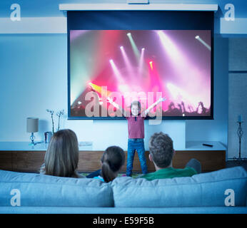 Family watching boy perform in front of concert screen Stock Photo