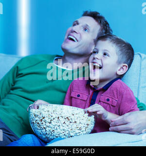 Father and son watching television on sofa Stock Photo