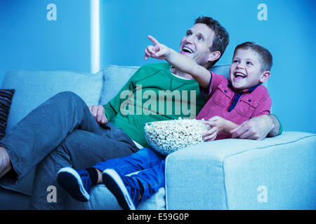 Father and son watching television in living room Stock Photo