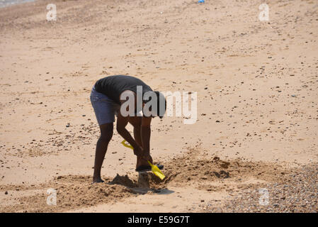Clacton-on-Sea, Essex, UK. 24th July, 2014. You're never two old to dig a hole on the beach. The beach is full of people enjoying the sunny weather on a hot day in Clacton-on-Sea Credit:  Matthew Chattle/Alamy Live News Stock Photo