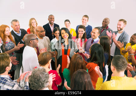 Business people clapping around businesswoman Stock Photo