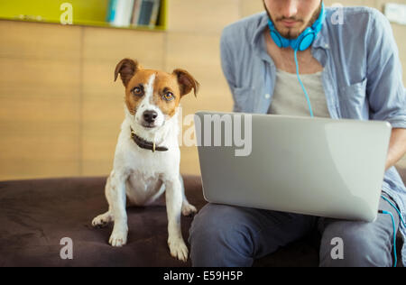 Dog sitting by man in office Stock Photo