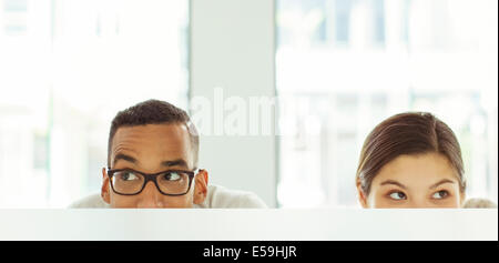 People peeking over cubicle in office Stock Photo