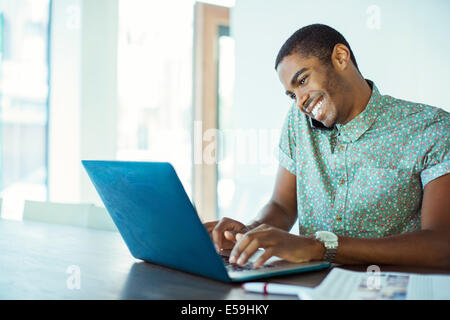 Man using laptop at desk in office Stock Photo
