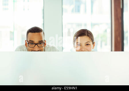 People peering over cubicle in office Stock Photo