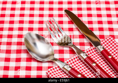 Red silverware on a red checkered napkin and table cloth Stock Photo
