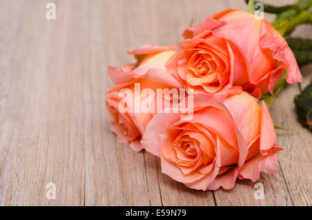 Three orange flowers of roses on wooden board Stock Photo