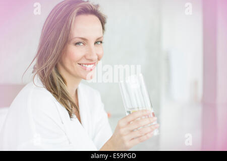 Woman having glass of water in bedroom