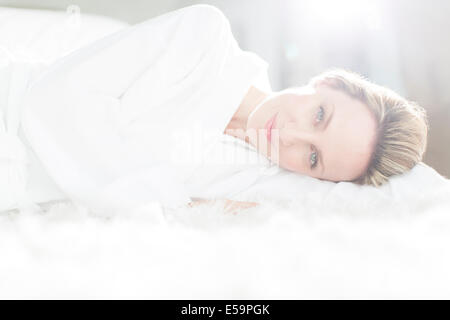 Woman in bathrobe laying on bed Stock Photo