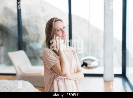 Woman talking on cell phone in modern living room Stock Photo