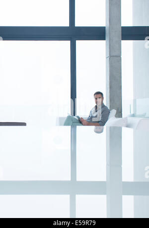 Man using cell phone on sofa in modern house Stock Photo