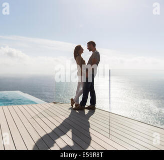 Couple on modern balcony overlooking ocean Stock Photo