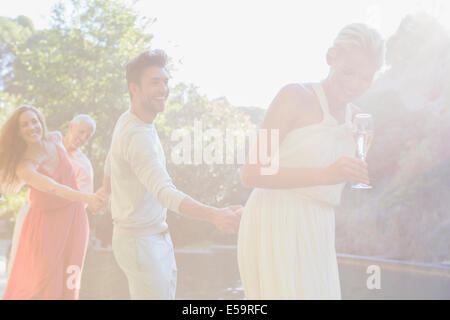 Friends holding hands by pool Stock Photo