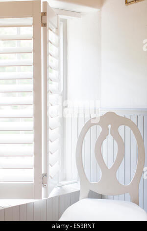 Chair by window with wooden blinds Stock Photo