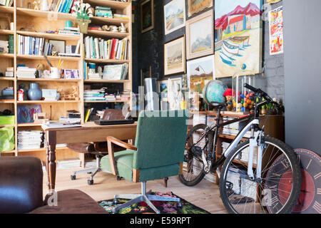 Desk, bookshelves and bicycle in study Stock Photo