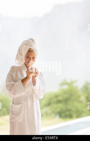 Woman in bathrobe having coffee outdoors