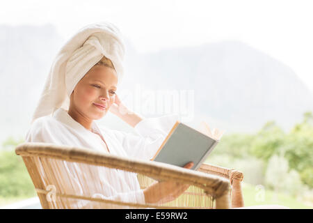 Woman in bathrobe reading outdoors